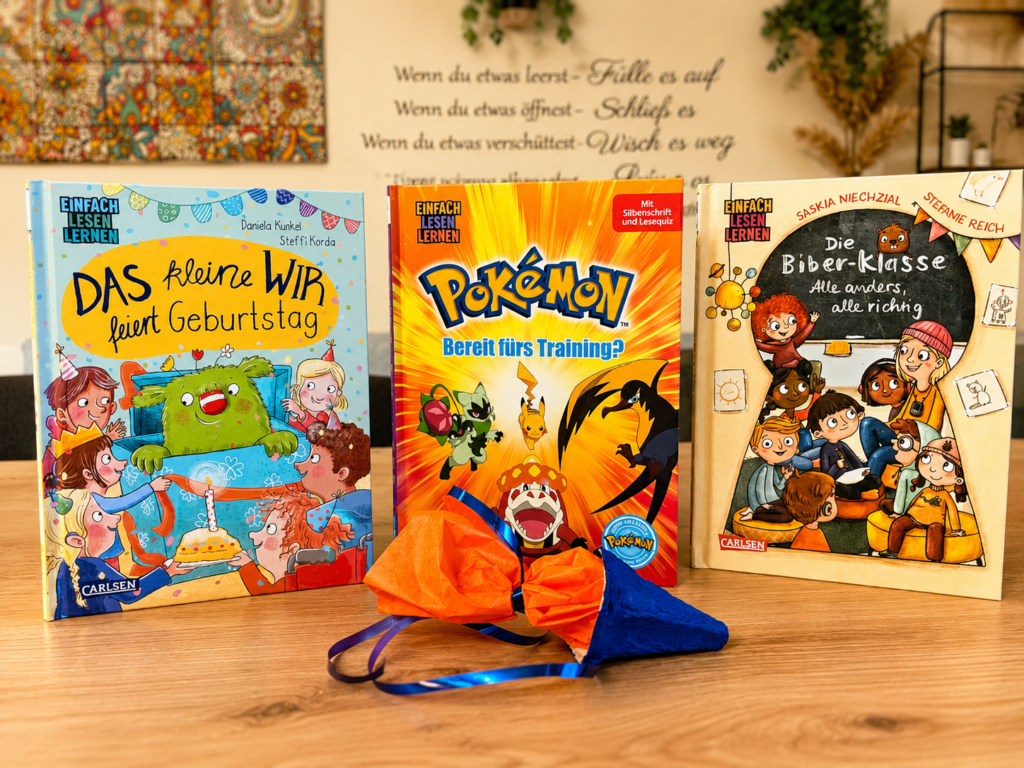 Drei bunte Kinderbücher für Leseanfänger stehen dekorativ auf einem Holztisch. Im Hintergrund sorgen eine selbst gebastelte Einschulungsgirlande aus Eierkartons und farbenfrohe Schulstartdekoration für eine fröhliche Atmosphäre. Die Bücher behandeln Freundschaft, Abenteuer und Vielfalt und eignen sich ideal für Kinder zum Schulanfang und die ersten eigenen Leseerlebnisse.